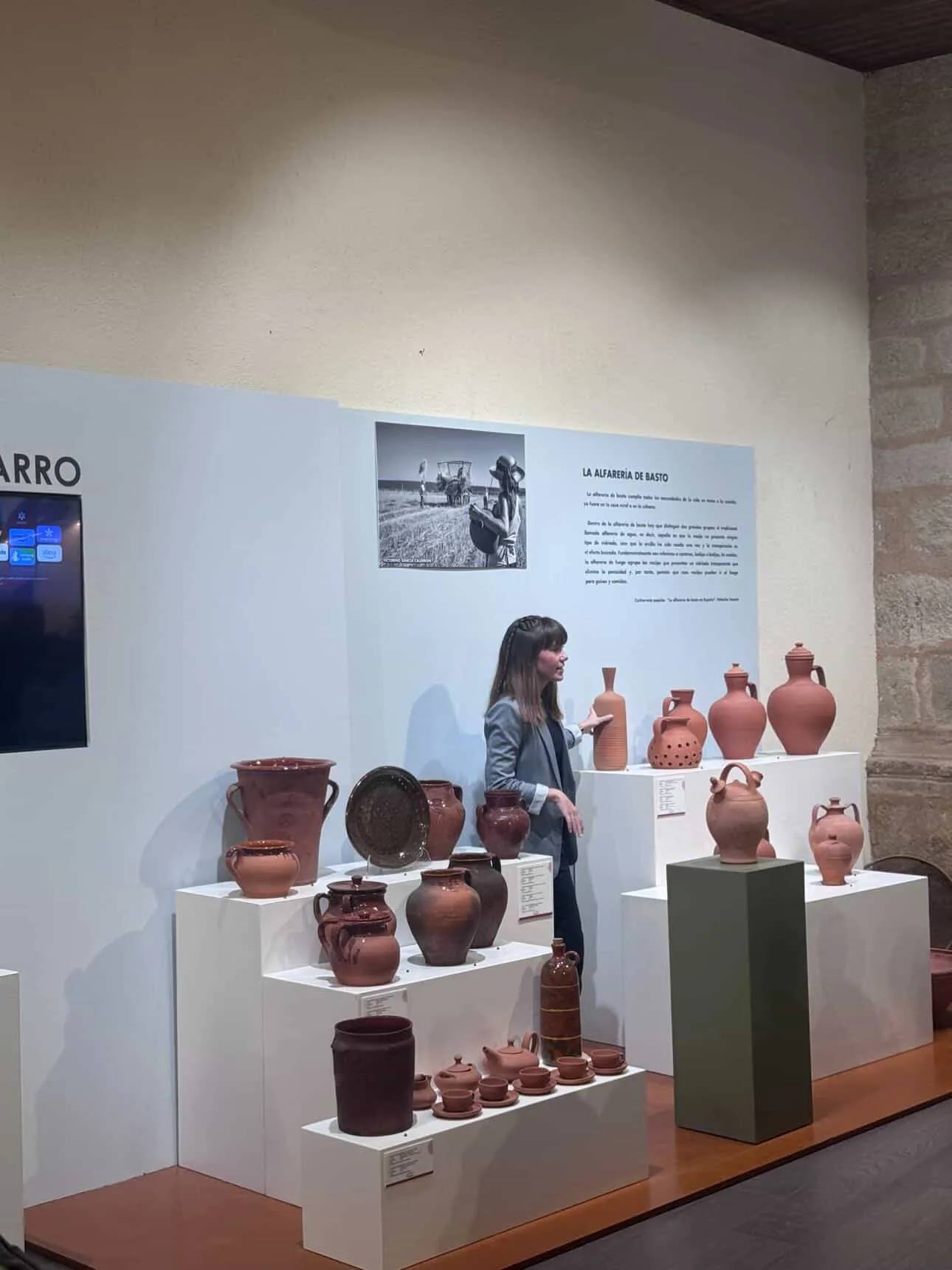 Elena explicando la alfarería de basto en el museo, junto a cántaros y botijos de barro